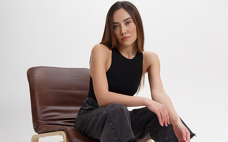 female sitting with relaxed fingers on a chair