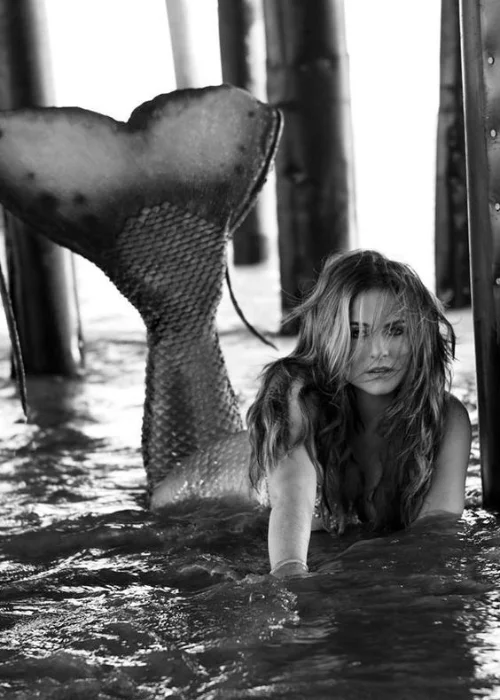 women posing as lying down mermaid